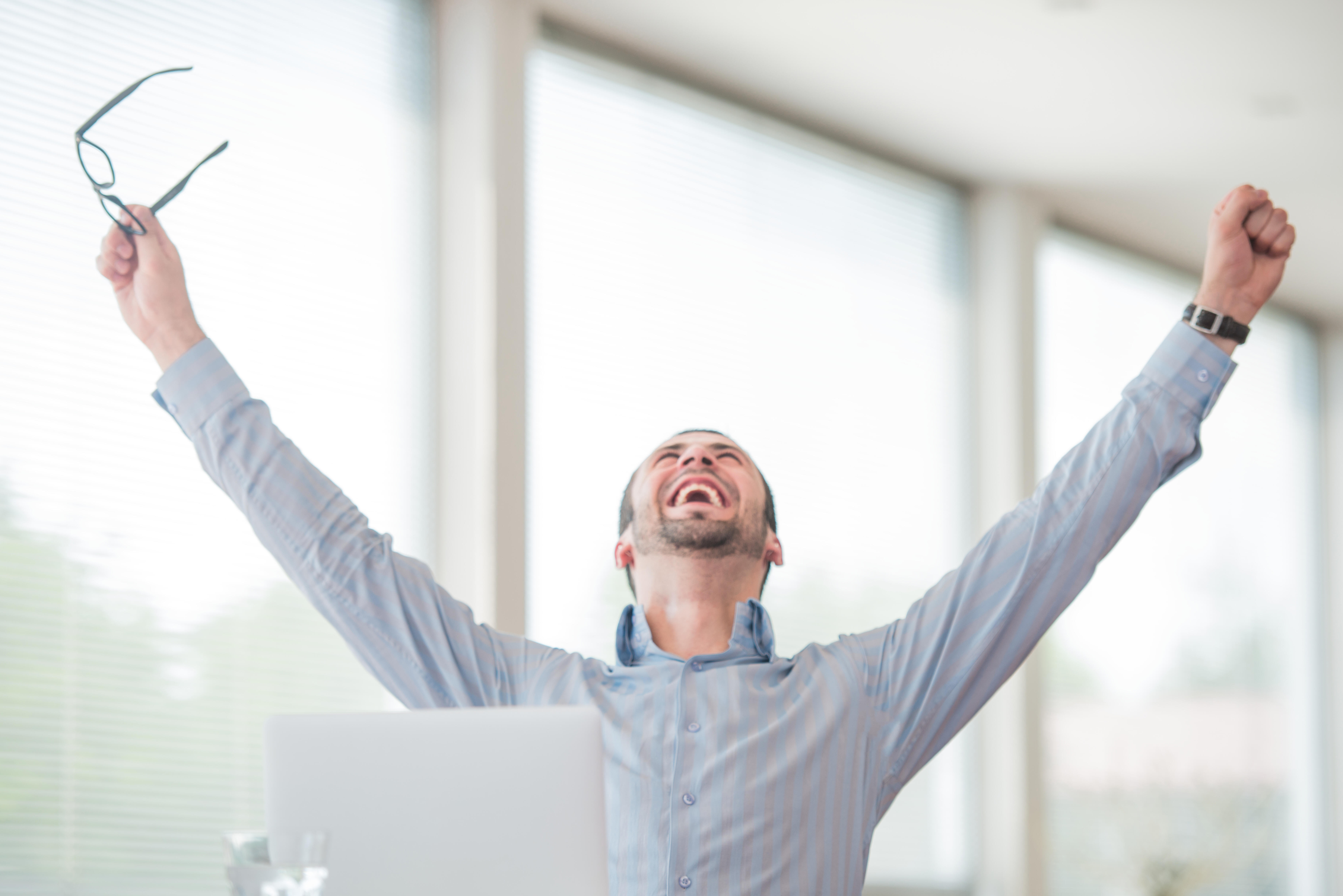 Victorious corporate man celebrating with his arms lifted in the air